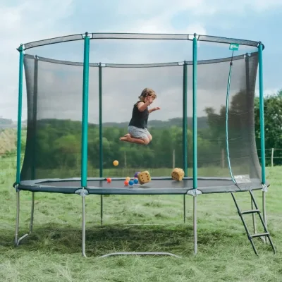 Bambino che salta su un tappeto elastico da giardino con rete di sicurezza