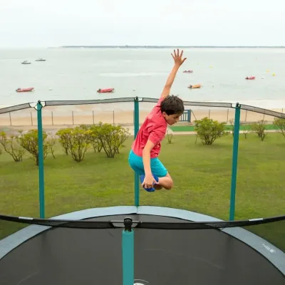 Bambino che salta su un tappeto elastico di fronte al mare
